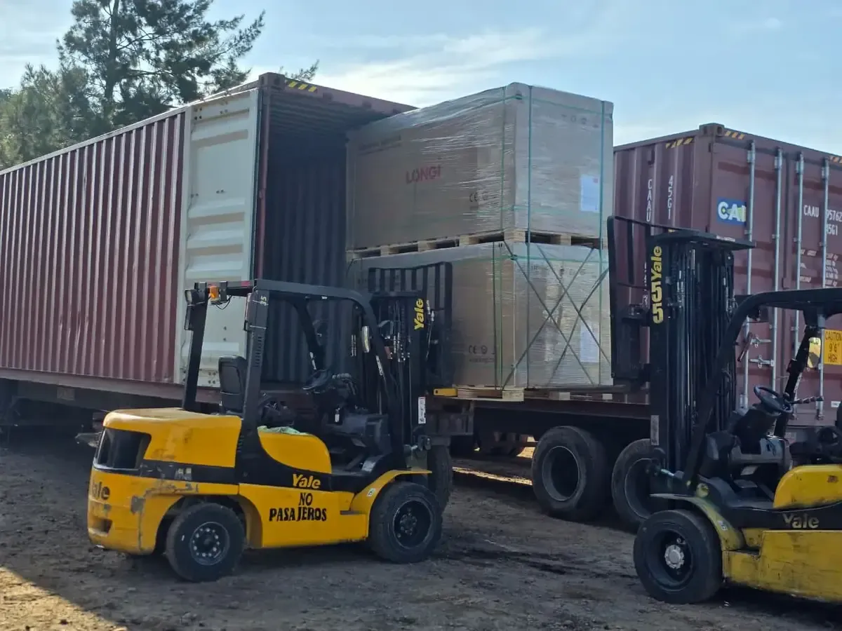 Montacargas cargando contenedores con paneles solares